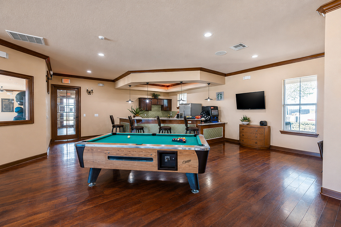 Elegant recreation room with a sleek billiards table, cozy bar area, and modern flat-screen TV, perfect for relaxation and entertainment.