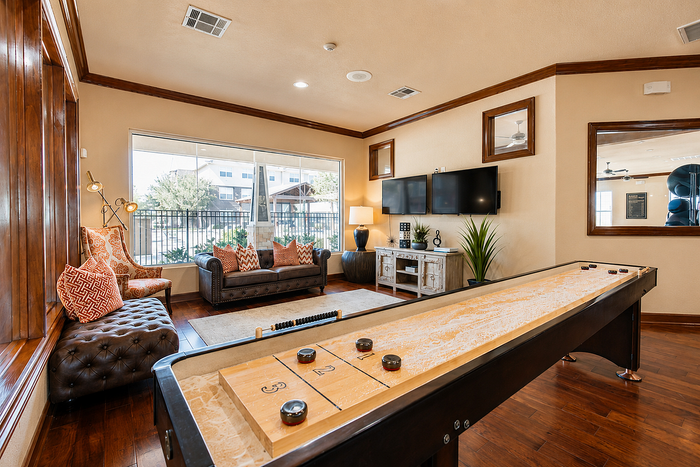Inviting entertainment room featuring a shuffleboard table, cozy seating area, and large windows for natural light.