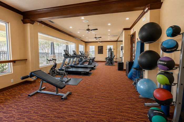 Inviting fitness center with modern exercise equipment, large windows providing natural light, and vibrant flooring.
