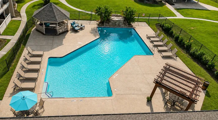 Aerial view of the swimming pool with organized lounge seating, gazebo, umbrella and shaded seating areas at The Reserve on Garth in Baytown, TX.
