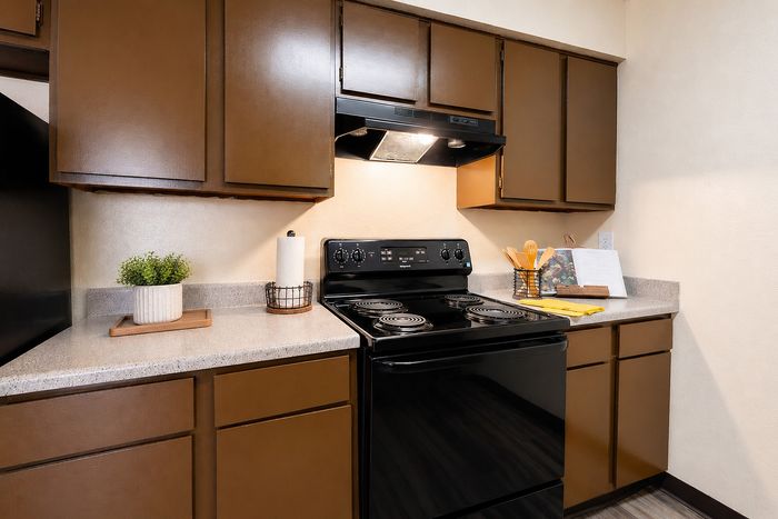 Apple Creek apartment kitchen with electric range, black appliances, ample cabinetry and countertop space.