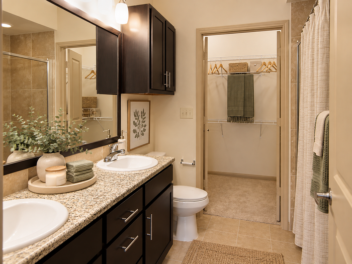 Bathroom at Valencia Place apartments in Houston, TX featuring a granite vanity, tiled shower area and adjoining walk-in closet.