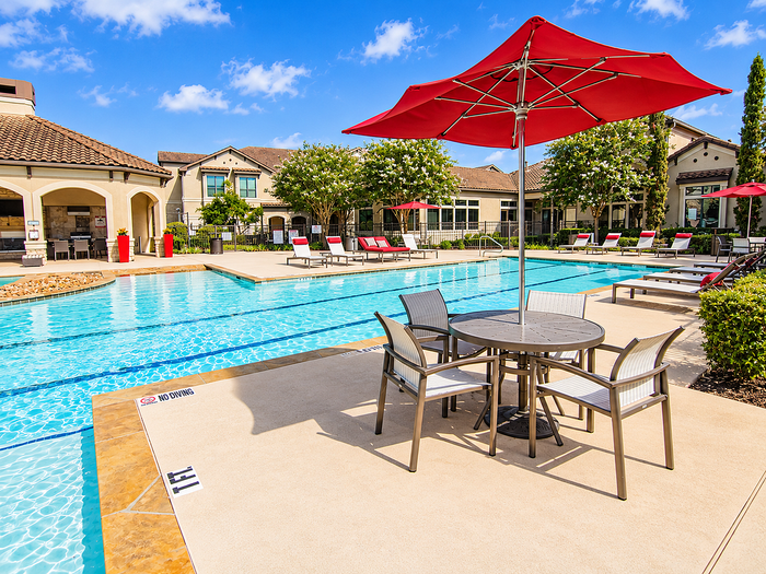 Aerial view of the resort-style swimming pool at Valencia Place apartments in Houston, TX with lounge seating, cabanas and landscaped pool deck.