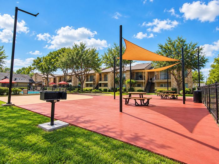 Outdoor recreation area with shade structures, picnic tables and grilling area at Parkside Apartments.