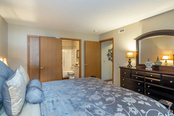 Cozy bedroom with elegant wooden furniture, soft lighting, and an ensuite bathroom for added convenience.