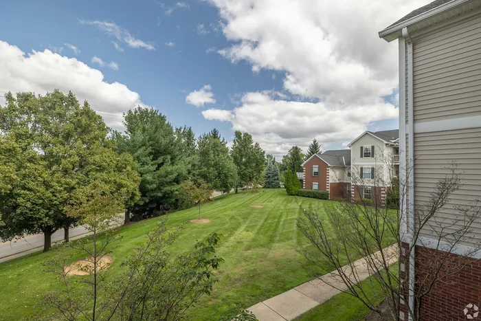 Charming apartment complex with lush green lawns and mature trees, offering serene outdoor spaces and picturesque views.