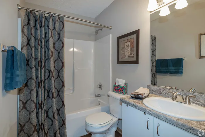 Contemporary bathroom showcasing elegant stone countertops, modern vanity, and stylish shower curtain for a luxurious feel.