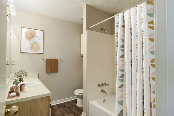 Charming bathroom with modern decor, featuring a stylish shower curtain, elegant vanity, and artistic wall print.