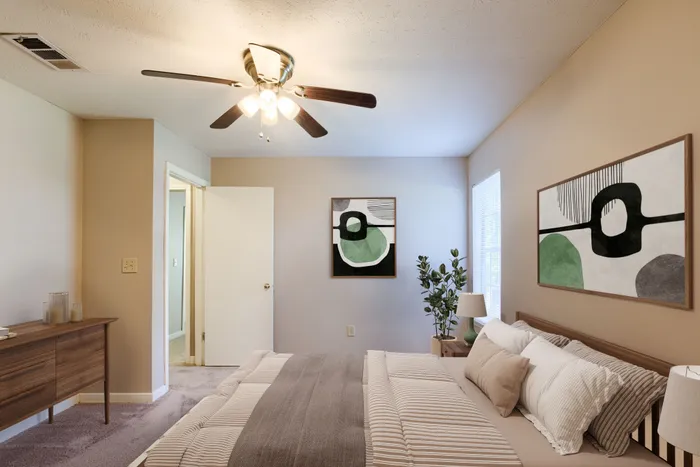Inviting bedroom with modern decor, featuring a cozy bed, stylish abstract artwork, and warm natural light.