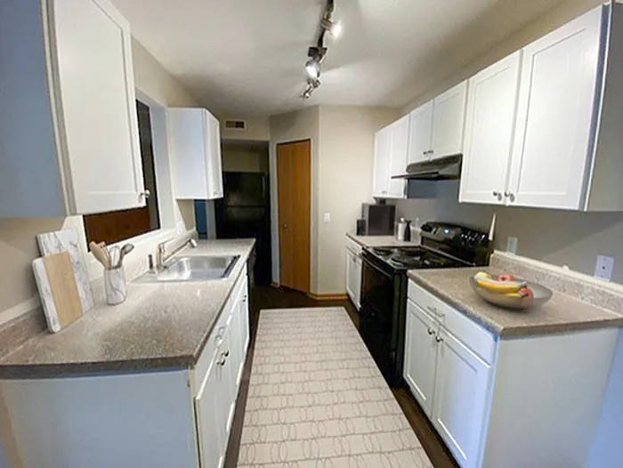 Modern kitchen with sleek white cabinets, elegant countertops, and stylish track lighting, offering a bright and inviting culinary space.