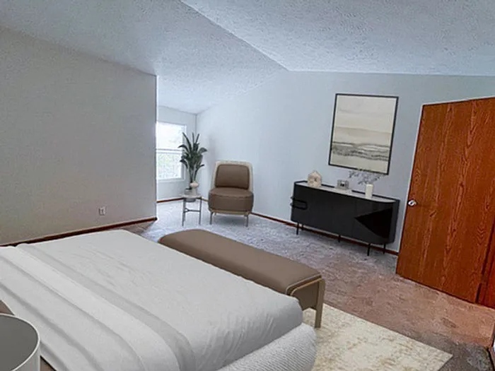 Bright and spacious bedroom with modern decor, featuring a large bed, cozy chair, elegant dresser, and natural light from a window.