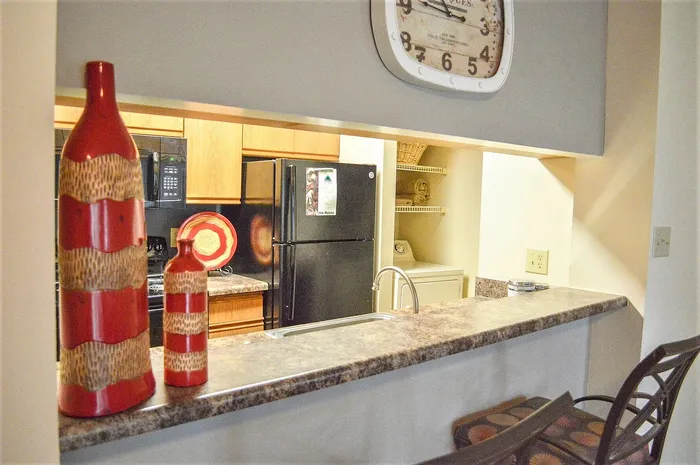 Charming kitchen view with elegant countertop, modern appliances, and artistic red decor bottles, perfect for stylish living.