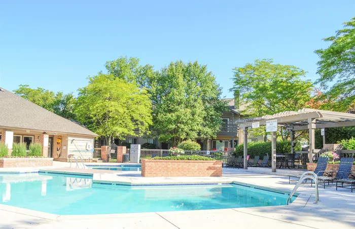 Inviting outdoor swimming pool surrounded by lush greenery and comfortable seating, perfect for relaxation and enjoyment on a sunny day.