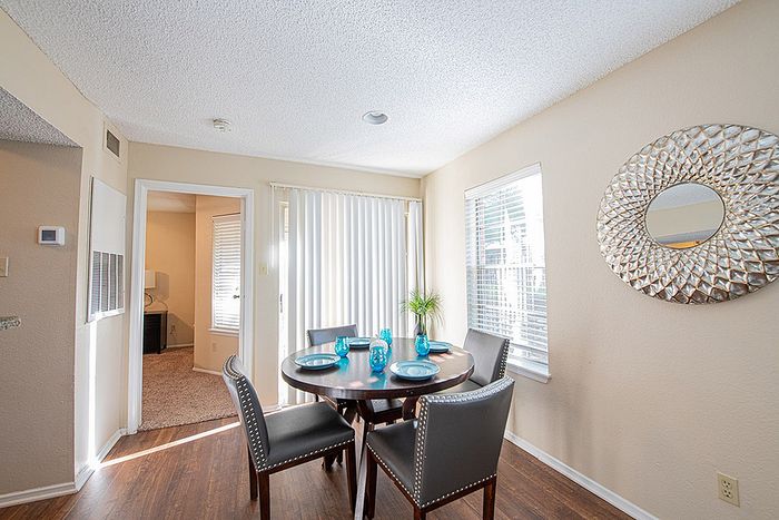 Bright dining area with elegant round table set for four, featuring stylish chairs and decorative wall mirror.