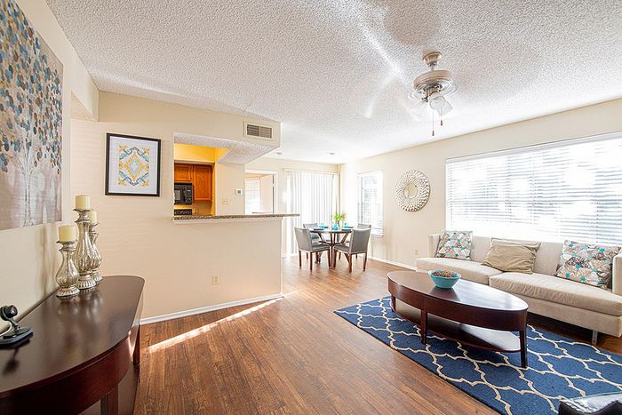 Bright and inviting living space with modern decor featuring a cozy sofa, stylish dining area, and an elegant open-plan kitchen.