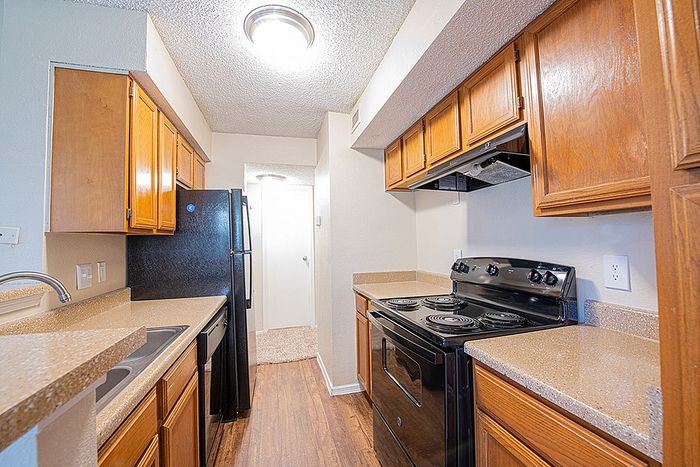 Charming kitchen with sleek black appliances, warm wooden cabinetry, and elegant countertops, offering a cozy and functional space.