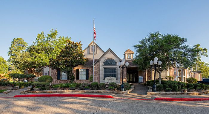 Charming apartment building entrance with classic architecture, surrounded by lush greenery and vibrant landscaping.