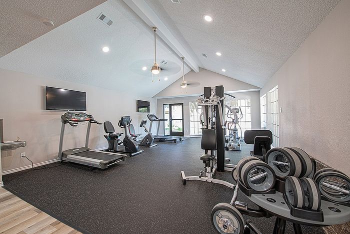 Bright and modern gym facility featuring state-of-the-art exercise equipment, including treadmills, stationary bikes, and weight machines in a spacious, airy setting.