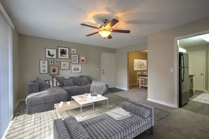 Inviting living room with a cozy grey sectional sofa, modern art gallery wall, and warm ambient lighting blending seamlessly into the dining area and kitchen.