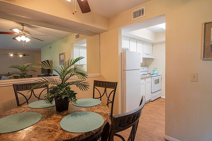 Inviting apartment dining area with elegant marble table, stylish decor, and a glimpse into a bright, well-equipped kitchen.