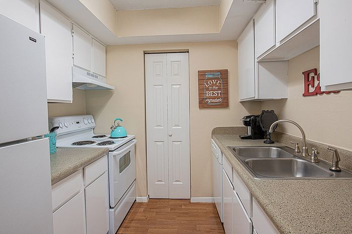 Charming kitchen with sleek white cabinets, modern appliances, and warm wooden flooring, perfect for culinary creativity.