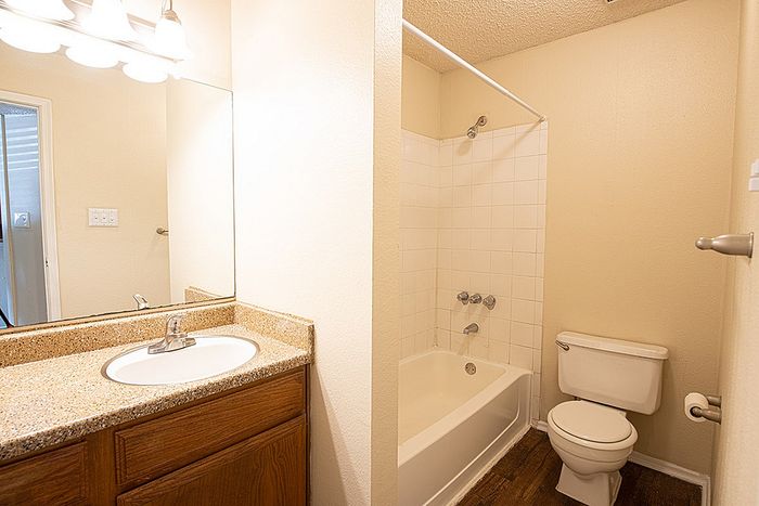 Bright, inviting bathroom with elegant vanity lighting, spacious mirror, and a cozy bathtub perfect for relaxation.