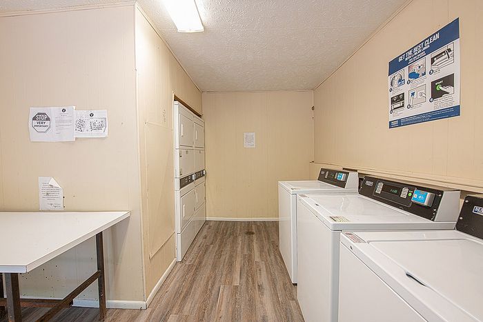 Bright and efficient laundry room with modern washers, dryers, and sleek wooden flooring offering convenient on-site amenities.