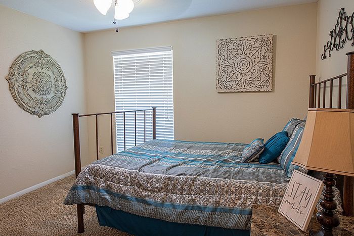 Cozy bedroom with elegant decor, featuring a comfortable bed with patterned linens, stylish wall art, and soft ambient lighting.