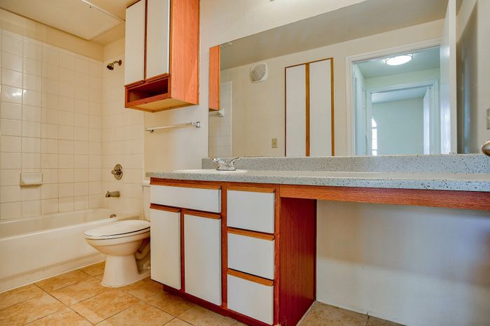 Inviting bathroom with a modern design featuring a spacious countertop, bright tiles, and ample storage.