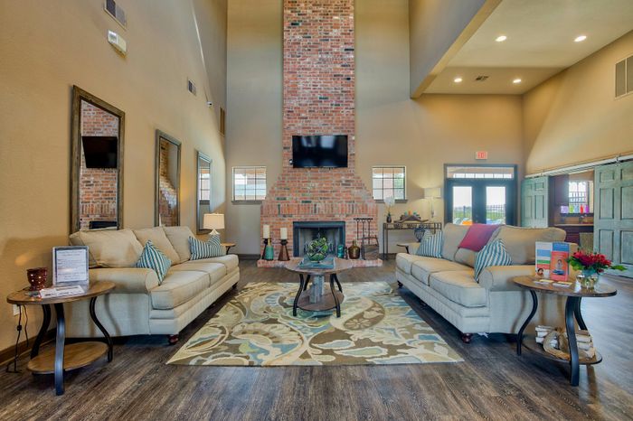 Inviting living room with elegant high ceilings, a rustic brick fireplace, and cozy seating area for relaxation.