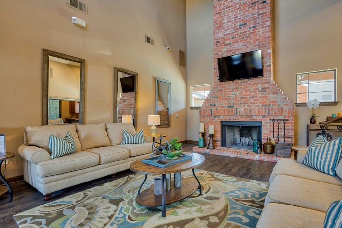 Inviting living room with plush sofas, a charming brick fireplace, and vibrant decor, perfect for cozy gatherings.