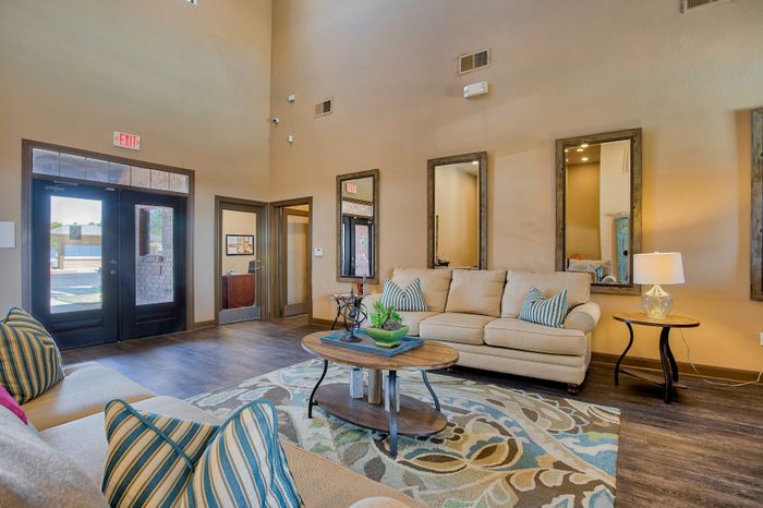 Inviting living room with high ceilings, cozy beige sofas, stylish striped cushions, and elegant rustic mirrors.