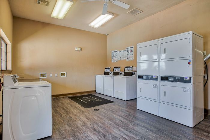 Modern laundry room featuring state-of-the-art washing and drying machines, bright lighting, and a clean, spacious layout.