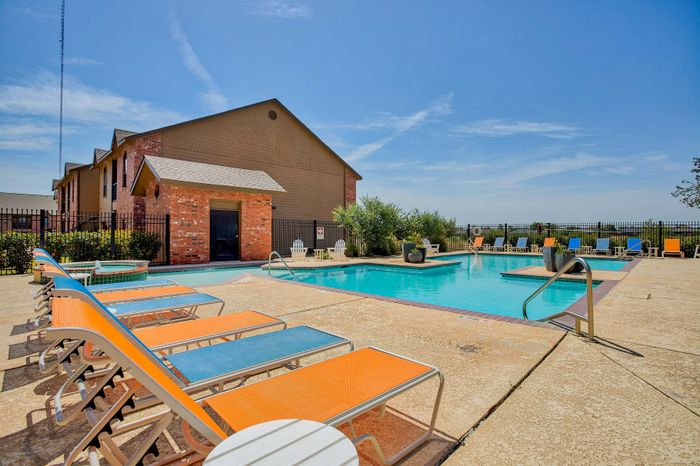 Vibrant outdoor pool area featuring colorful lounge chairs and a refreshing swimming pool under a clear blue sky.