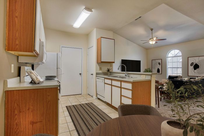 Charming open-plan kitchen with modern appliances, leading to a cozy living area with large arched window and stylish decor.