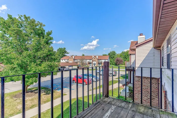 Inviting balcony view with lush greenery and charming townhouse architecture, perfect for relaxing in a serene neighborhood.