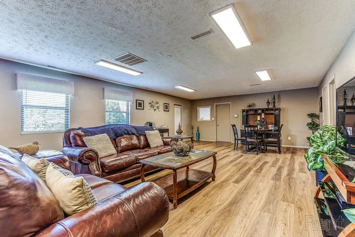 Inviting living space with elegant leather sofas, a cozy dining area, and stylish wood flooring, ideal for relaxation and entertaining.