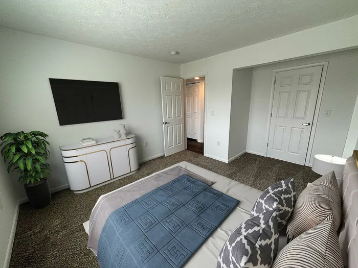 Modern and inviting bedroom with stylish decor, featuring a plush bed, contemporary dresser, and elegant wall-mounted TV, bathed in natural light.