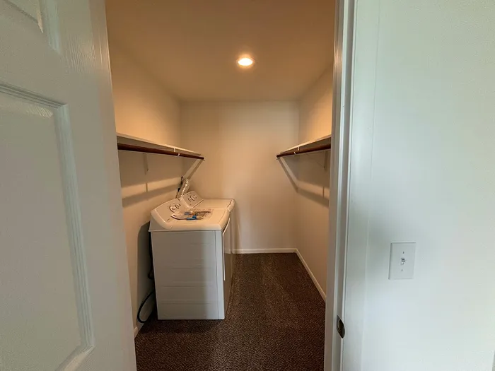 Spacious laundry room with a modern washer and dryer, ample shelving, and warm lighting for a cozy, functional space.