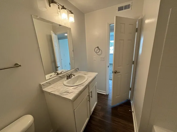 Bright modern bathroom with elegant marble countertop, large mirror, and sleek fixtures.