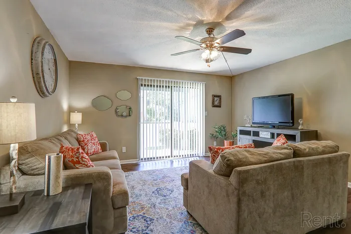 Charming living room with cozy sofas, vibrant decor pillows, and a soothing ceiling fan, perfect for relaxation.