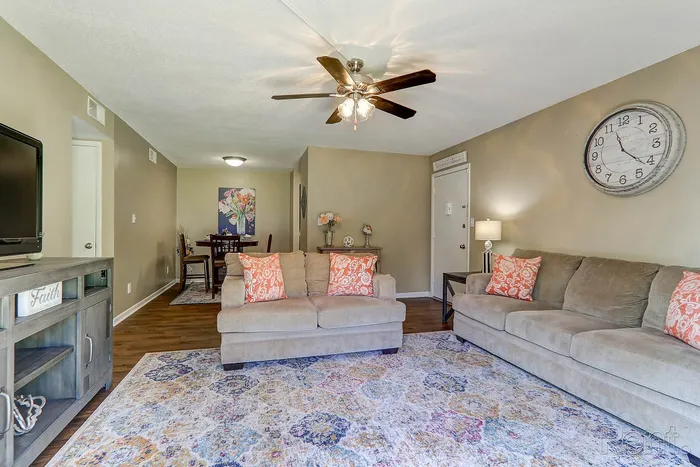 Inviting living room with plush sofas, vibrant patterned rug, and elegant decor, featuring a cozy dining area in the background.