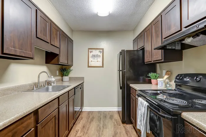Modern kitchen with elegant dark wood cabinets, sleek appliances, and stylish countertops, offering a warm and inviting atmosphere.