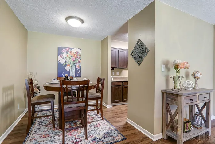 Charming dining area with elegant wooden furniture, floral artwork, and tasteful decor leading into a cozy kitchen.
