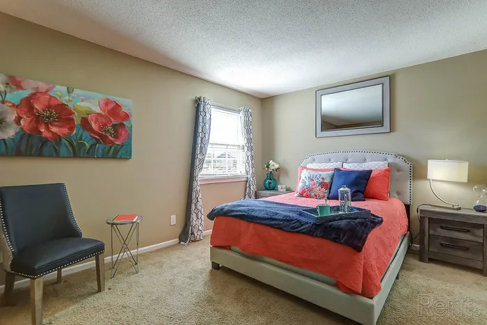 Charming bedroom with elegant decor, featuring a plush bed, vibrant floral artwork, and soft natural lighting from a large window.