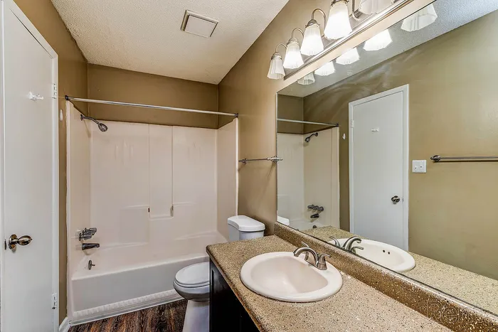 Elegant bathroom with modern lighting, spacious countertop, and classic bathtub set against warm-toned walls.
