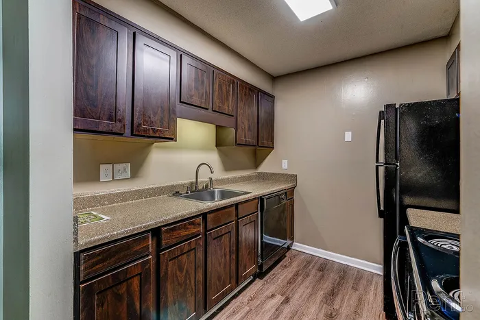 Charming kitchen with rich wooden cabinets, sleek countertops, modern appliances, and warm lighting, offering a cozy culinary space.