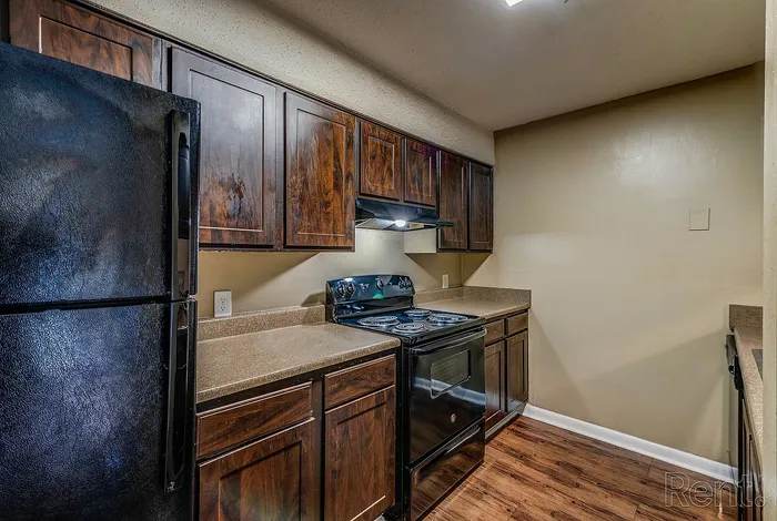Charming kitchen featuring rich wooden cabinetry, sleek black appliances, and elegant countertops, perfect for culinary creativity.