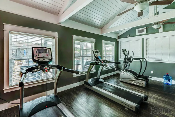 Bright fitness room with modern treadmills, dark wooden floors, and large windows offering scenic views.