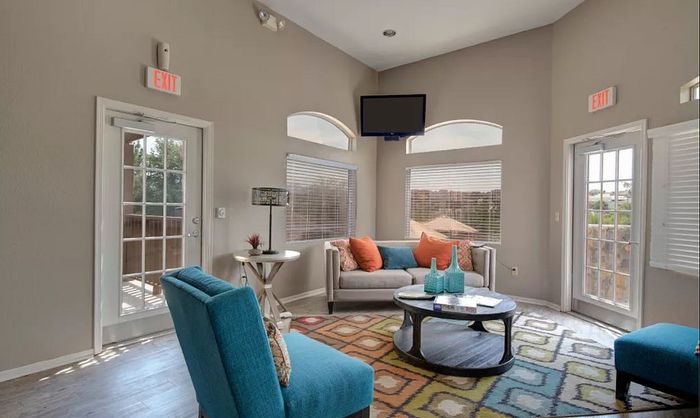 Bright and inviting living room with stylish furniture, colorful accents, large windows, and access to a balcony.